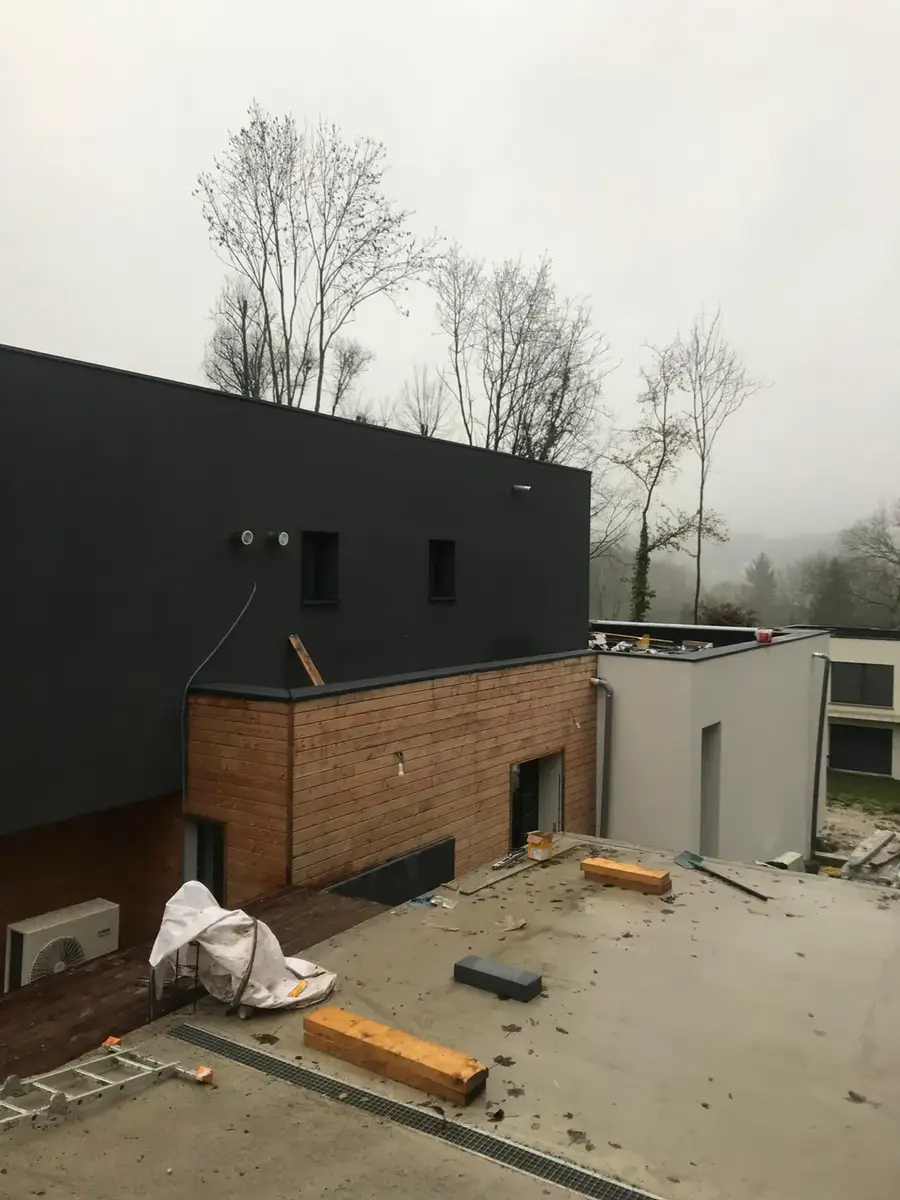 Maison contemporaine, façade bardée et enduit foncé